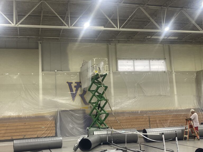 Indoor gymnasium with ventilation ducts and construction materials laid out for renovation at VR facility