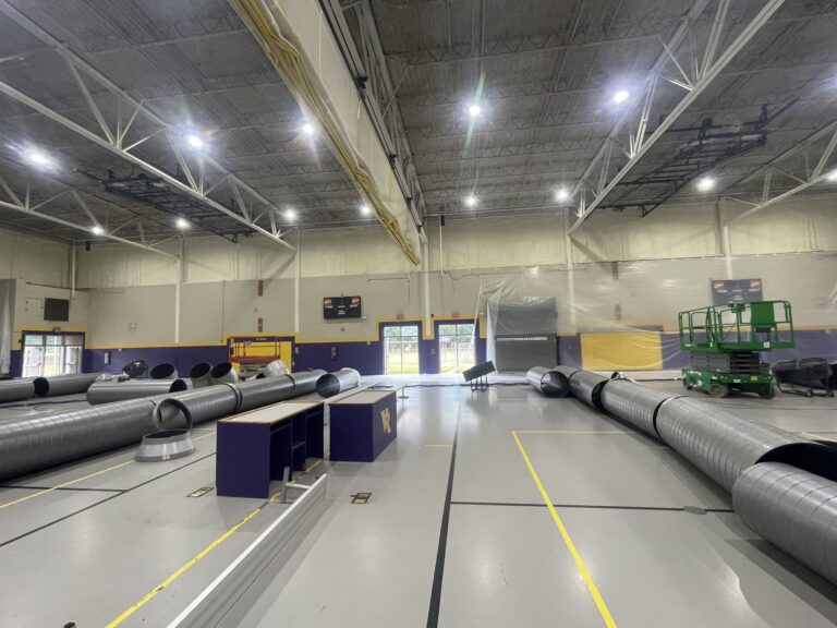 Indoor gymnasium with ventilation ducts and construction materials laid out for renovation at VR facility