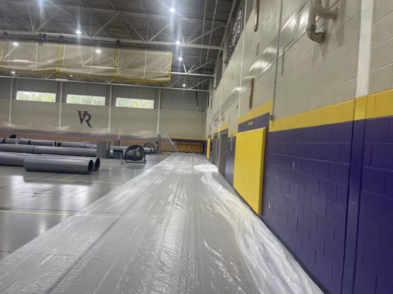 Indoor gymnasium with ventilation ducts and construction materials laid out for renovation at VR facility