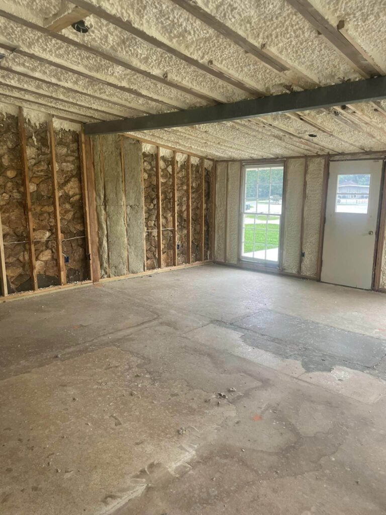 Room under renovation with spray foam insulation applied to ceiling and walls with exposed studs